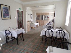 a restaurant with white tables and chairs and a kitchen at Stoneleigh Hotel in Skegness