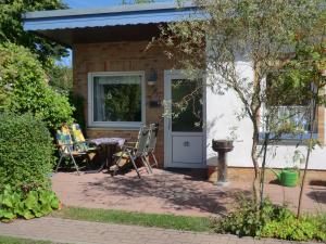 un patio con mesa y sillas frente a una casa en Bungalow Ungers Welt 1 en Ostseebad Nienhagen