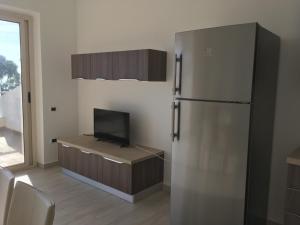 a kitchen with a refrigerator and a table with a television at Appartamenti Sole a Zambrone Village in Zambrone