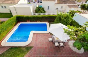 een zwembad met twee parasols en stoelen ernaast bij Fig Tree Villa in Orihuela-Costa