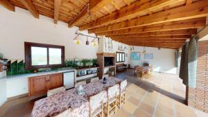 a large kitchen with wooden ceilings and a long table at Agroturisme Can Burguès in Santa Eulalia de Ronsaná