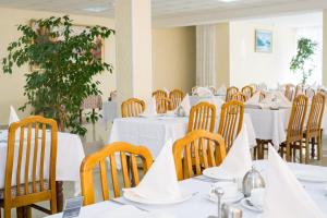 Health Resort Dolina Narzanov Nalchik في نالتشيك: غرفة طعام مع طاولات وكراسي بيضاء