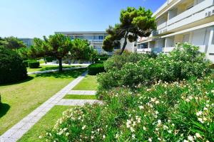 un giardino di fronte a un edificio con alberi e fiori di Isaresidence Holiday Resort a Ca Lino
