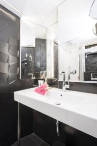 La salle de bains est pourvue d'un lavabo blanc et d'un miroir. dans l'établissement Hotel Icône, à Paris
