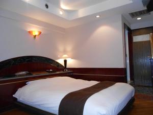 - une chambre avec un grand lit et une tête de lit en bois dans l'établissement Hotel Lumiere Gotenba (Adult Only), à Gotemba
