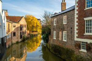 un canal en una ciudad con edificios y árboles en Riverside City Loft Apartment, en York