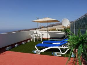 - un balcon avec une table, des chaises et un parasol dans l'établissement Casa Angel y Carmen (La Dama, La Gomera), à El Cercado