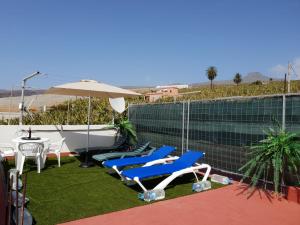 a patio with chairs and an umbrella and a bathtub at Casa Angel y Carmen (La Dama, La Gomera) in El Cercado