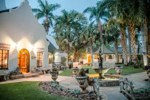 a house with palm trees and a fountain at Loskop Valley Lodge in Groblersdal