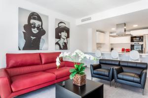 マルベーリャにあるby RIVA - Gorgeous 2 Bedroom Apartment in Centre of Puerto Banusのリビングルーム(赤いソファ、椅子2脚付)