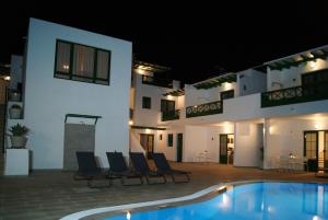 a pool in front of a hotel at night at Apartamentos Zalabar in Tías
