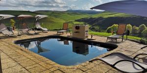 einen Pool mit Stühlen und einem Sonnenschirm in der Unterkunft Amazian Mountain River Lodge in Underberg