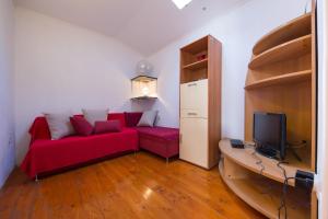 salon z czerwoną kanapą i telewizorem w obiekcie Strma Apartments w mieście Vis