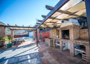 a patio with an outdoor kitchen with a brick oven at Las Huertas in Monachil