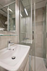 a white bathroom with a sink and a shower at Hôtel du Dauphin in Lyon