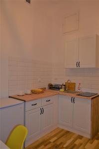 uma cozinha com armários brancos e uma cadeira amarela em Apartament Meiselsa 2. em Cracóvia