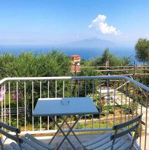 uma mesa e cadeiras numa varanda com vista para o oceano em Sorrento Olive Tree Garden em Sorrento