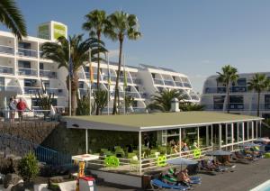 ein Resort mit Leuten, die vor einem Gebäude auf Stühlen sitzen in der Unterkunft Ereza Apartamentos Los Hibiscos - Adults Only in Puerto del Carmen