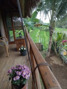 a porch with flowers and a palm tree at Babahan Farmstay in Tabanan
