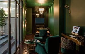 パリにあるHôtel du Rond-point des Champs-Élysées - Esprit de Franceの緑の壁と椅子、テーブルが備わるお部屋