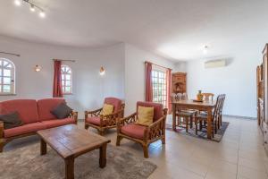 ein Wohnzimmer mit einem Sofa, Stühlen und einem Tisch in der Unterkunft Villa Nora by Gabi Miguel in Albufeira