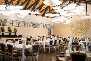 a banquet hall with white tables and chairs and chandeliers at The Royal Senchi Hotel and Resort in Oko Sombo