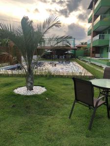 a table and a chair next to a palm tree at Apartamento alto padrao in Tamandaré