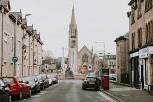 a city street with cars parked in front of a church at The King Street Holiday Apartment in Inverness City Centre in Inverness