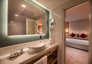 a bathroom with a sink and a mirror and a bed at Astral Maris Hotel in Eilat