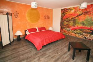 a bedroom with a red bed and a painting of a bridge at Kunsthof Eibenstock in Eibenstock