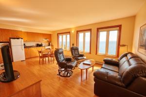 a living room with a couch and chairs and a kitchen at Condos-Hotels Natakam, Communauté Autochtone in Les Escoumins