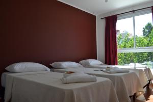 three beds in a room with a large window at Apart Porto del Sol by CPH in Villa Carlos Paz
