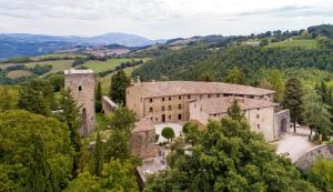 un antiguo castillo en las colinas con árboles en Castello Di Petroia Dimora d'Epoca, en Gubbio