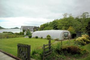 a large greenhouse in a yard next to a house at The Galley Of Lorne Inn in Ardfern