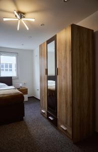 a bedroom with a large wooden cabinet with a mirror at Boardinghouse Apart-Hotel in Oberkochen