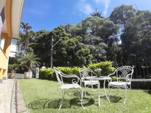 três cadeiras e uma mesa na relva em Pousada Palacio de Cristal em Petrópolis