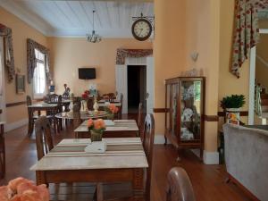 uma sala de jantar com mesas e um relógio na parede em Pousada Palacio de Cristal em Petrópolis