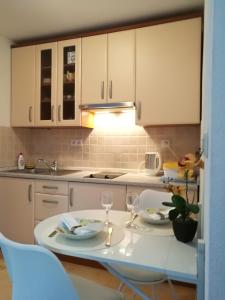 uma cozinha com armários brancos e uma mesa com dois copos em Studios Bilonic em Split