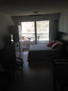 a bedroom with a bed and a balcony with a table at Edificio Go Pocitos in Montevideo