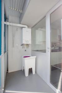 La salle de bains blanche est pourvue d'un lavabo blanc et d'une fenêtre. dans l'établissement Liiiving in Porto | Bright Light Apartment, à Porto