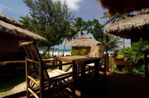 a wooden table and chairs on a deck with the beach at Palm Leaf Resort Koh Tao in Ko Tao
