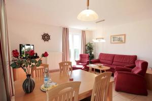 uma sala de estar com uma mesa e um sofá vermelho em Residenz Falkenberg by Rujana em Ostseebad Sellin