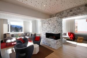 a living room with a stone fireplace and chairs at Hotel Elite in Crans-Montana