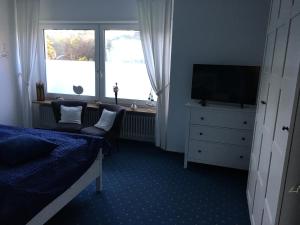 a bedroom with a bed and a tv and a window at Haus Pamela Wohnung A in Neuharlingersiel