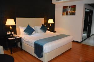 a bedroom with a large white bed with blue pillows at The Olive Hotel, Juffair in Manama