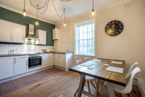 a kitchen with a wooden table and a clock on the wall at Walmgate Cottage in York