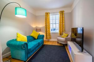uma sala de estar com um sofá azul e almofadas amarelas em Walmgate Cottage em York