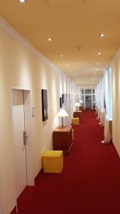 un couloir avec une rangée de chaises et un tapis rouge dans l'établissement Schlosshotel Domäne Walberberg, à Bornheim