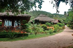 a house with a thatch roof and a road at Palm Leaf Resort Koh Tao in Ko Tao