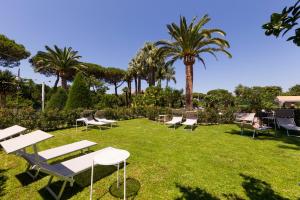 a group of chairs and tables in a park with palm trees at Hotel Alpha in Sant'Agnello
